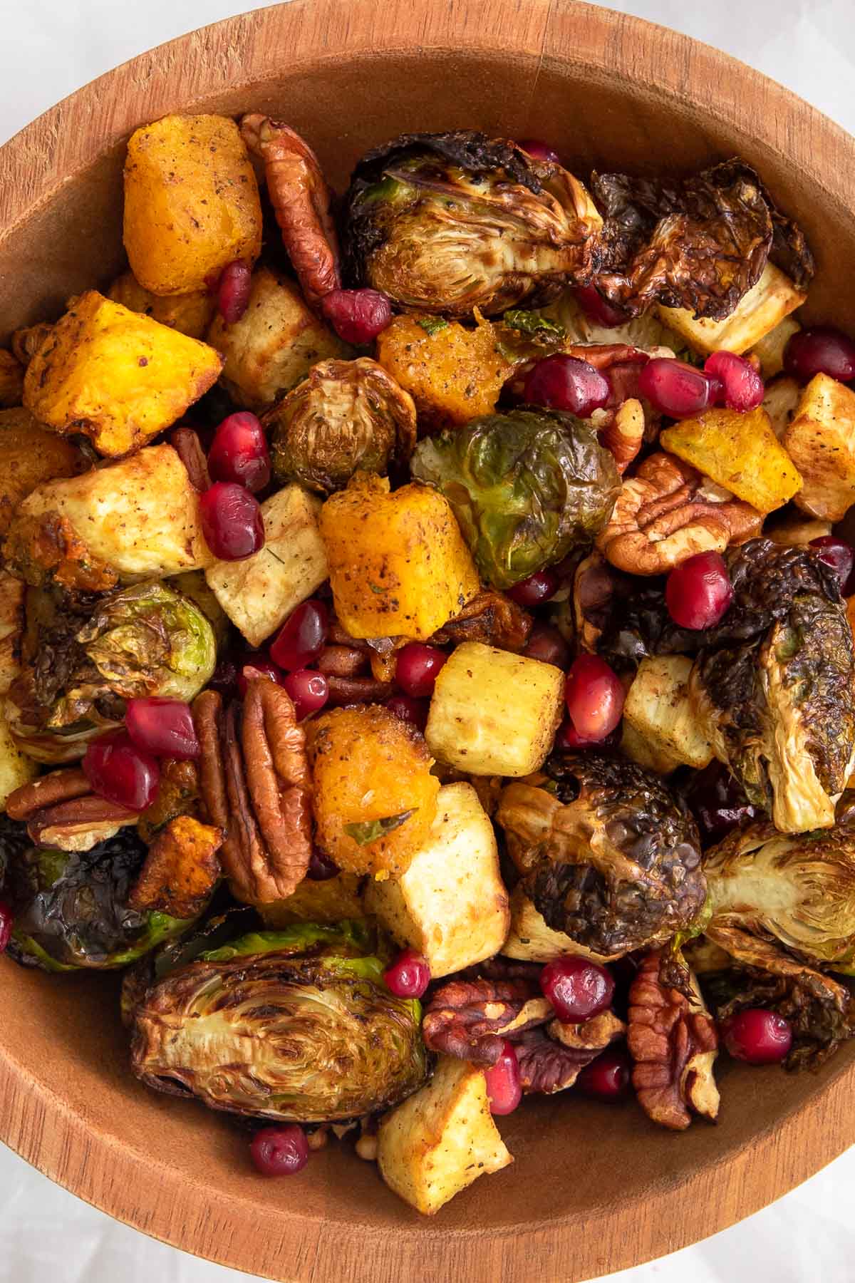 Roasted butternut squash, brussels sprouts, parsnips, and pecans in a bowl.