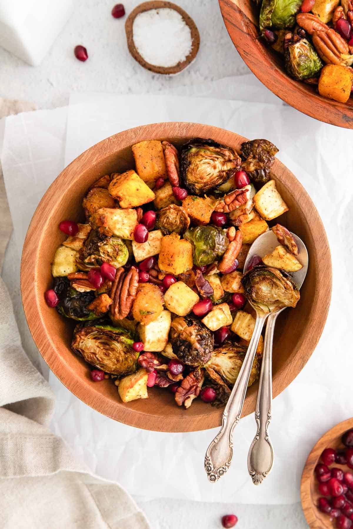 Roasted vegetables in a wooden bowl with a serving spoon.