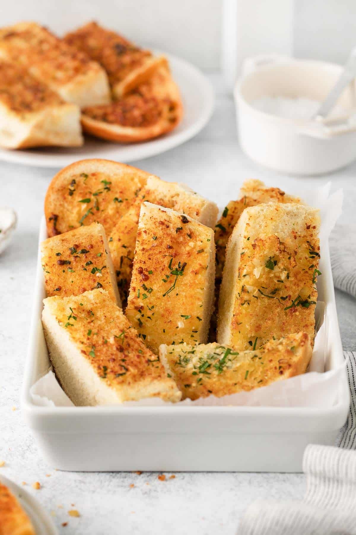 A white bowl filled with garlic bread.