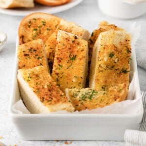 A white bowl filled with garlic bread.