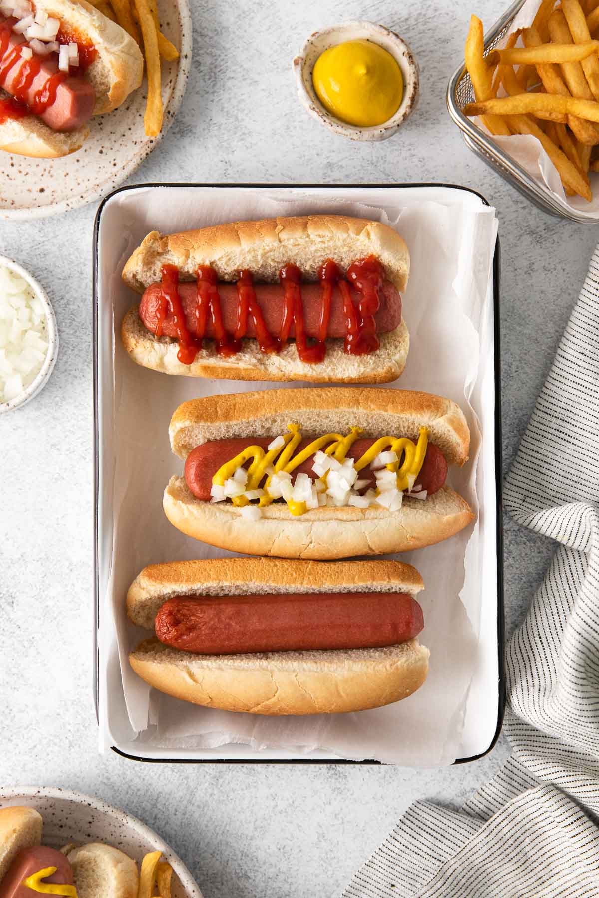Three hot dogs with toppings on a serving platter.