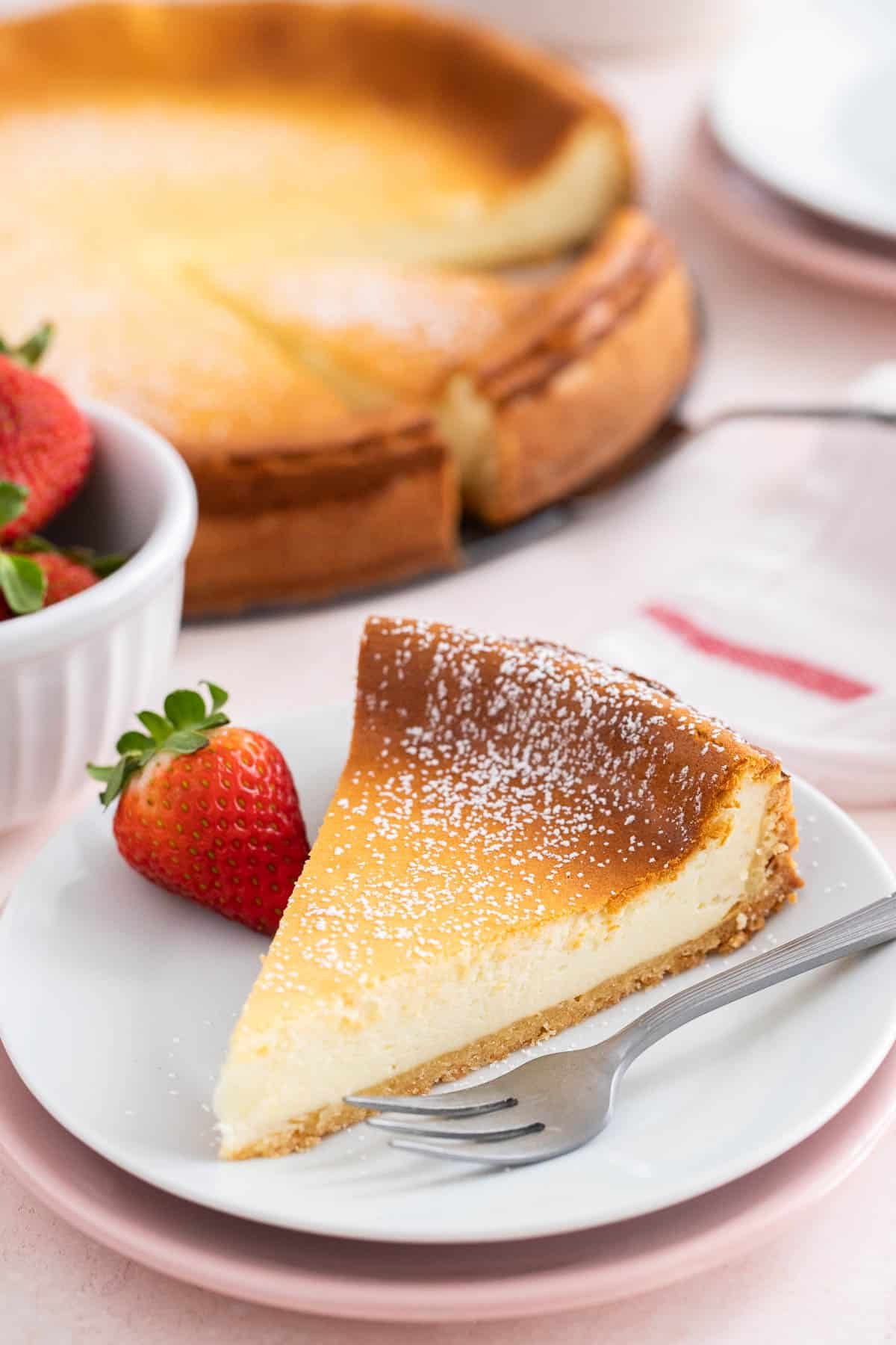 A slice of cheesecake on a white plate with a fork next to it.
