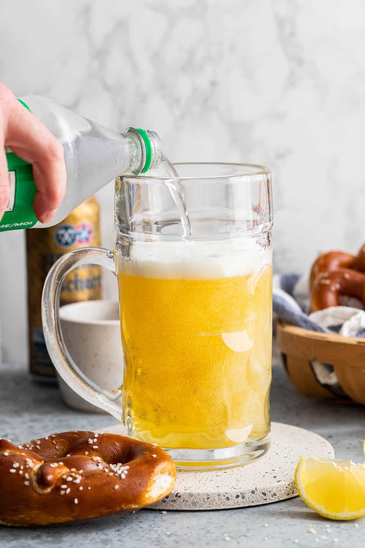 Sparkling lemonade being poured into a beer stein filled with beer.