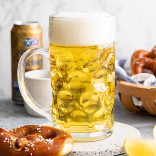 A beer stein next to a pretzel and a slice of lemon.