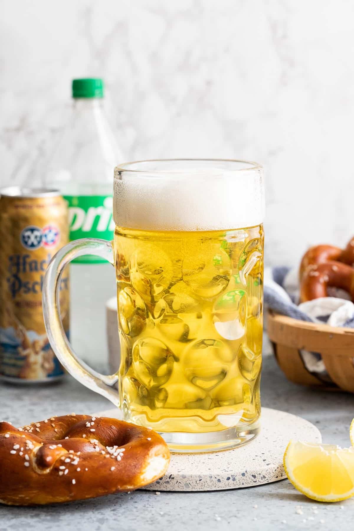 A beer stein next to a pretzel and a slice of lemon.