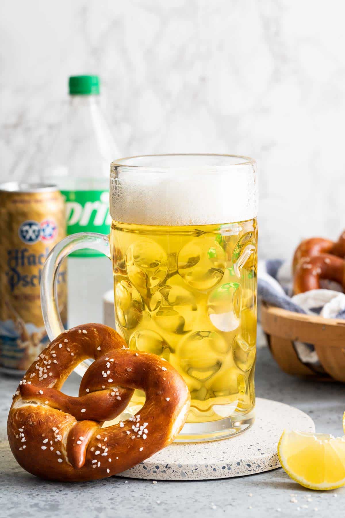 A pretzel leaning on a beer stein filled with Radler.