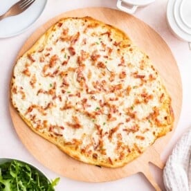 A Flammkuchen on a wooden board.