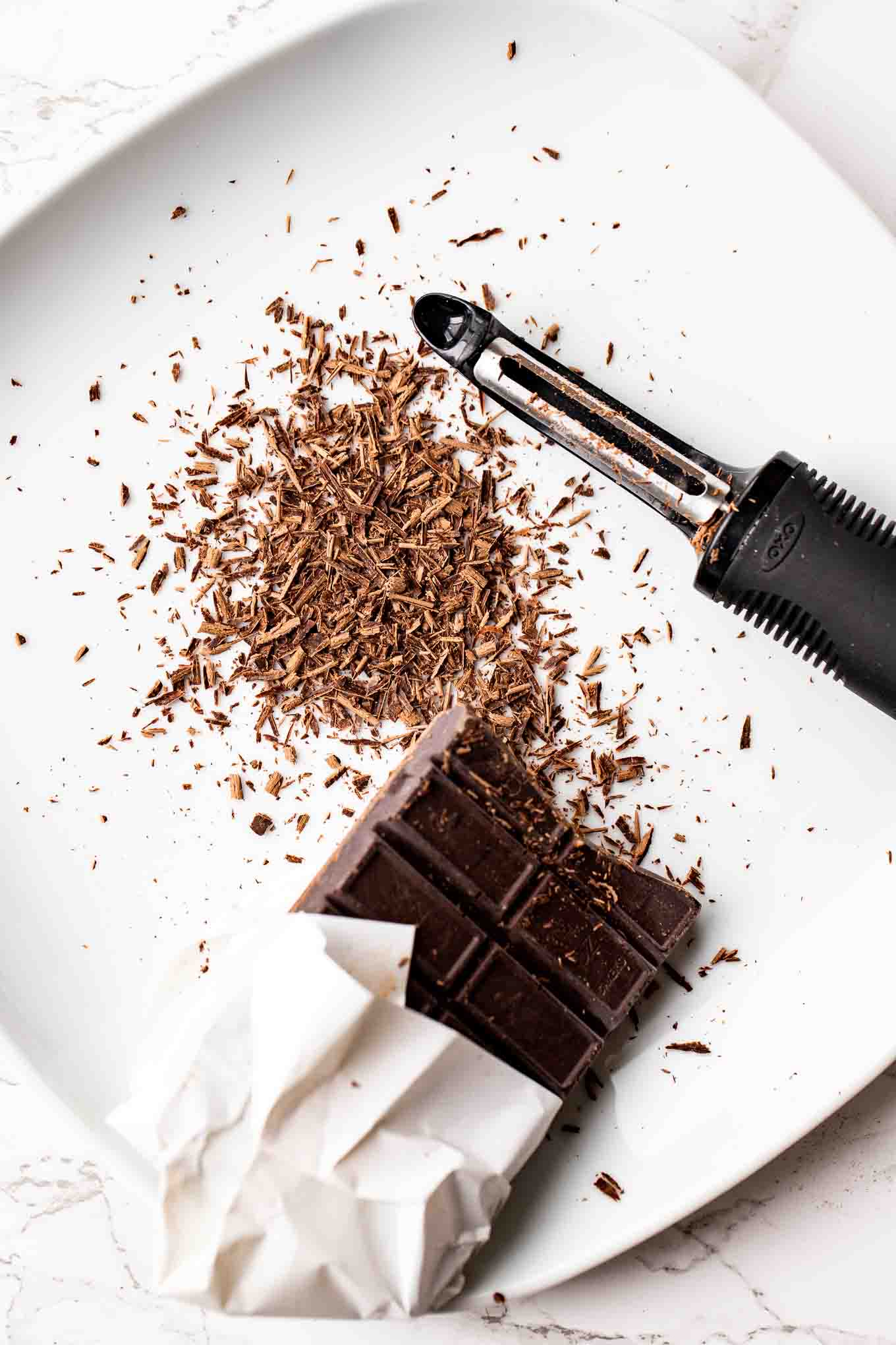 A chocolate bar and a vegetable peeler on a plate.