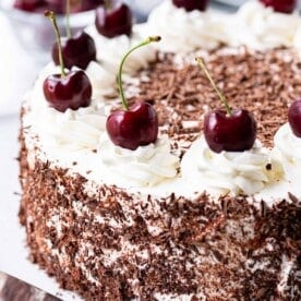 A Black Forest cake decorated with cherries on a cake platter.