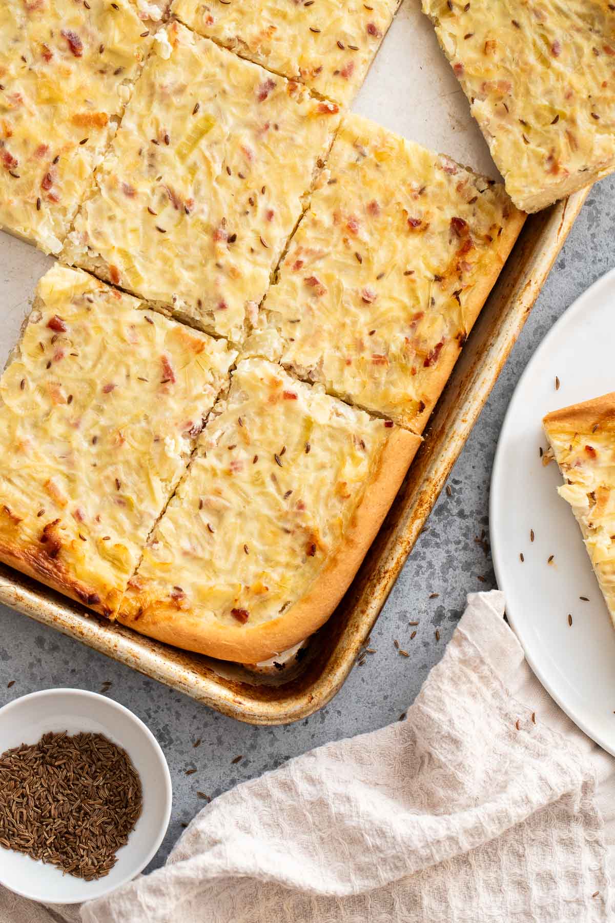 Zwiebelkuchen on a plate and on a baking sheet.