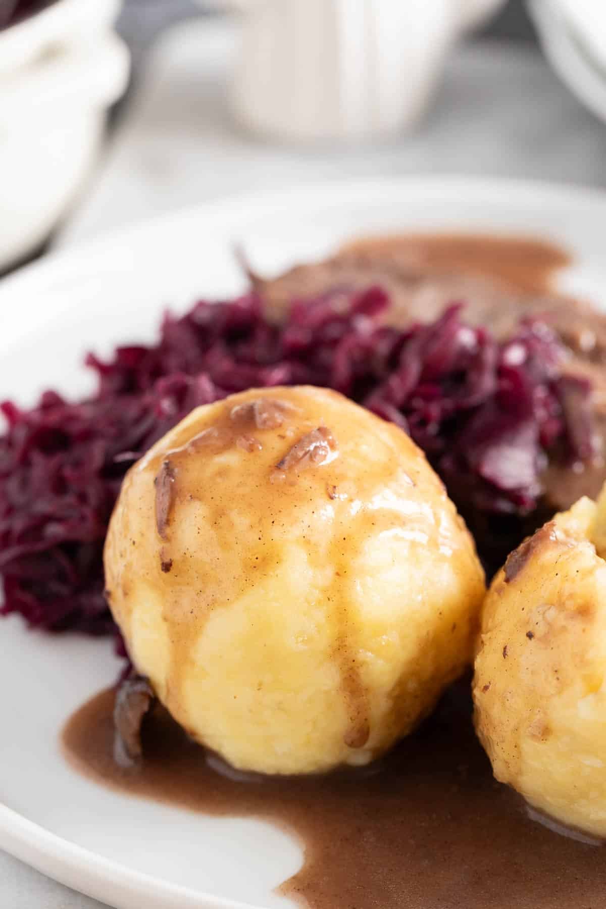 Kartoffelkloesse with gravy, Sauerbraten, and red cabbage on a plate.