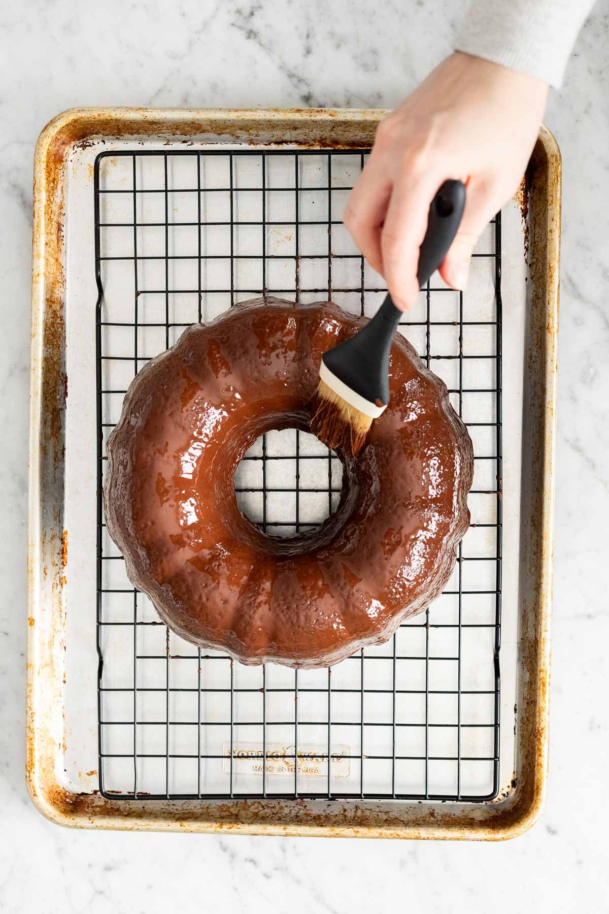 Brushing a cake with chocolate glaze.
