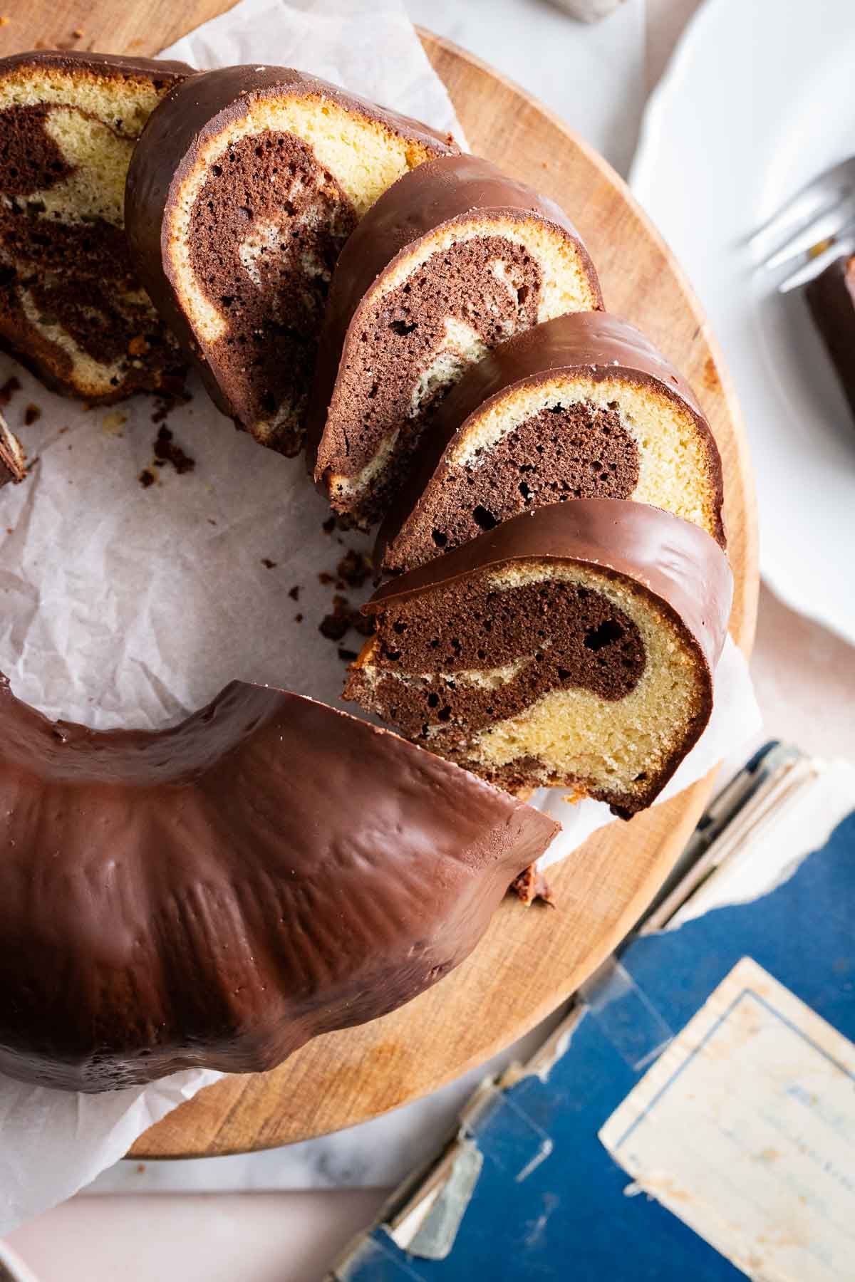 A bundt cake on a cake stand with a recipe book next to it.