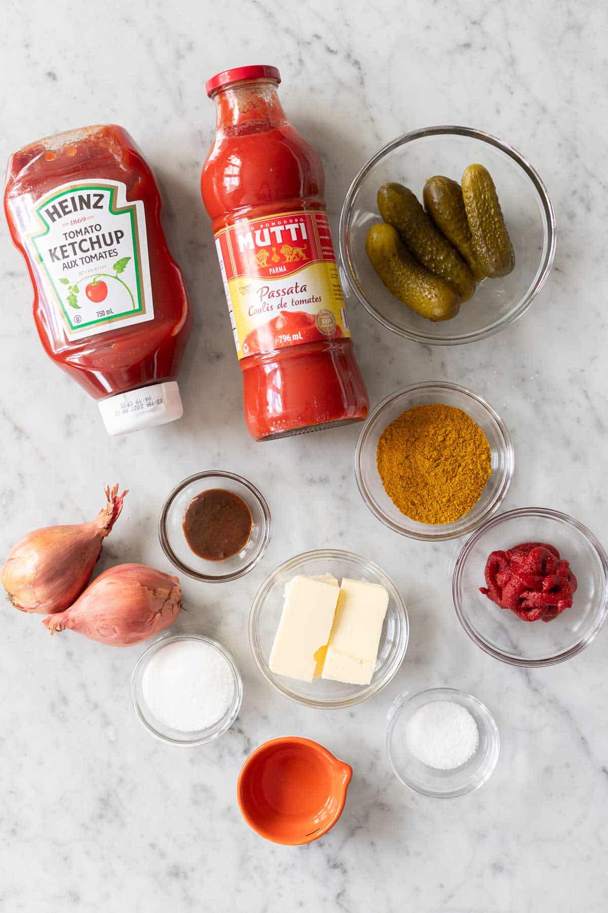 Ingredients for homemade currywurst sauce including passata, curry powder, and the secret ingredient: German pickles.